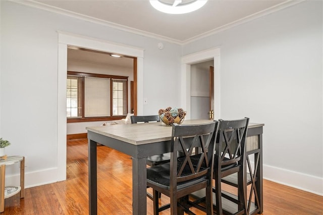 dining room with baseboards, wood finished floors, and crown molding