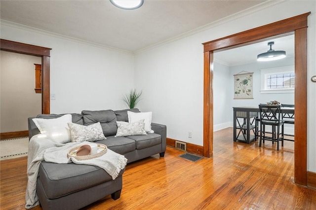 living area with visible vents, ornamental molding, baseboards, and wood finished floors