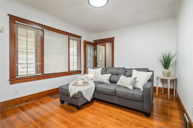 living room with light wood-style flooring, crown molding, baseboards, and a healthy amount of sunlight