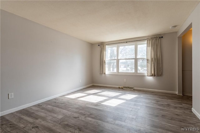 unfurnished room with visible vents, wood finished floors, and baseboards