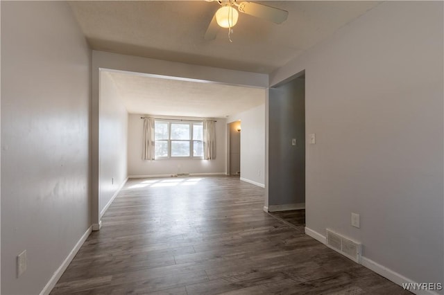 unfurnished room with dark wood finished floors, visible vents, baseboards, and a ceiling fan