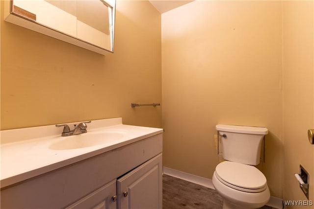 bathroom with toilet, vanity, and baseboards