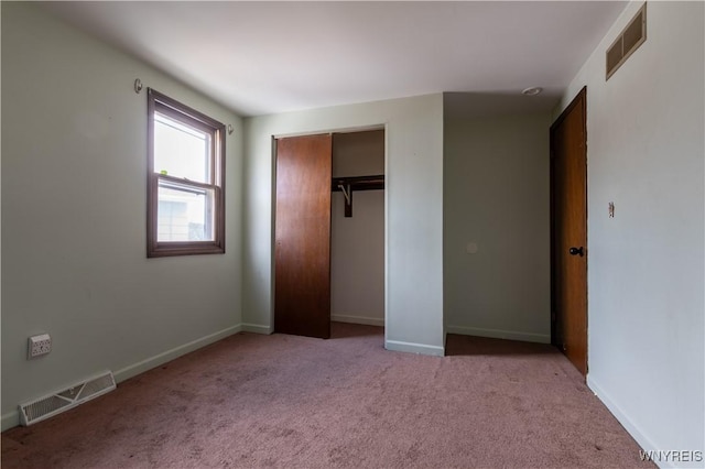 unfurnished bedroom with a closet, visible vents, light colored carpet, and baseboards