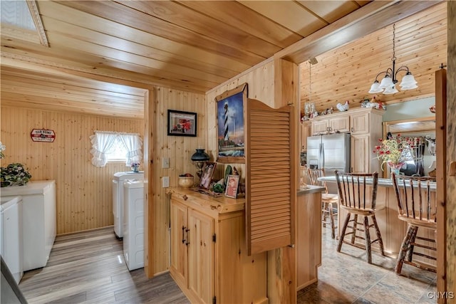 kitchen with washer and dryer, a notable chandelier, wood ceiling, and a breakfast bar area