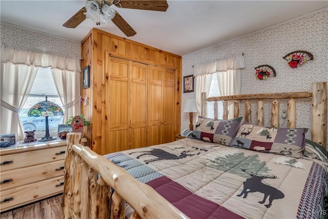 bedroom with wallpapered walls, a ceiling fan, a closet, and ornamental molding