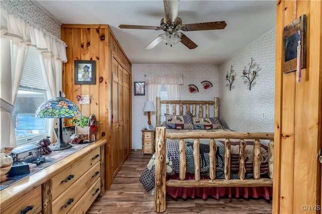 bedroom with wallpapered walls, light wood-style floors, and a ceiling fan