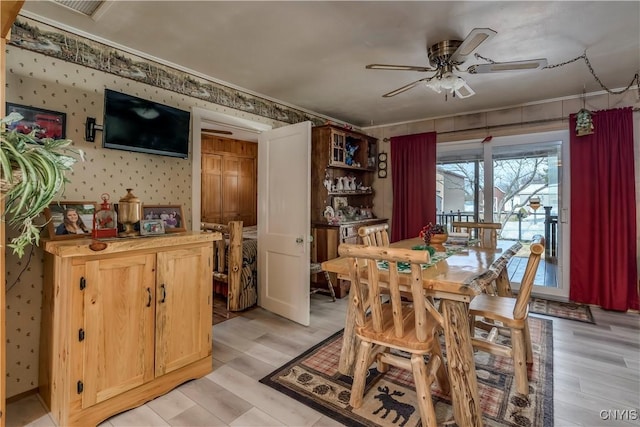 dining area with light wood-type flooring, visible vents, a ceiling fan, and wallpapered walls