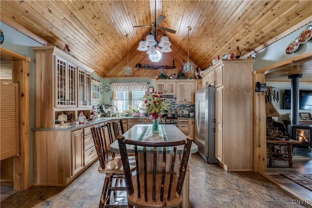 kitchen featuring a wood stove, freestanding refrigerator, vaulted ceiling, wooden ceiling, and tasteful backsplash