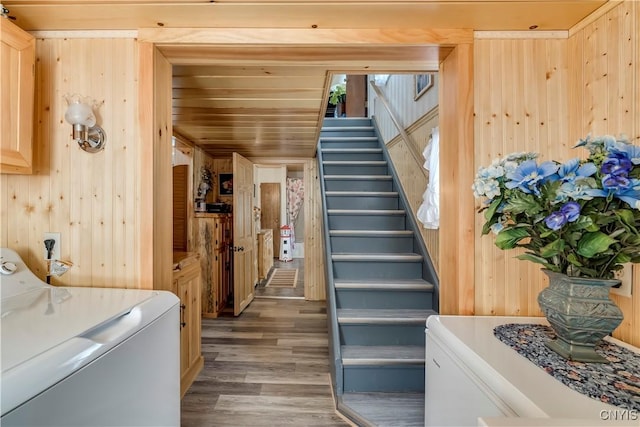 stairway with washer / dryer, wood walls, and wood finished floors