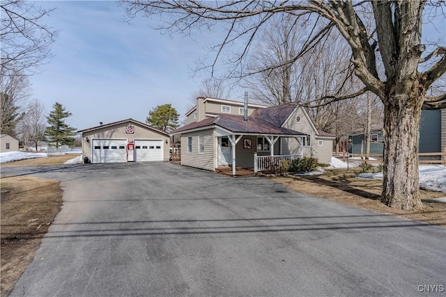 view of front of property featuring an outbuilding, covered porch, a detached garage, and aphalt driveway