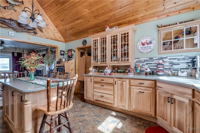 kitchen featuring light brown cabinets, lofted ceiling, light countertops, wooden ceiling, and backsplash