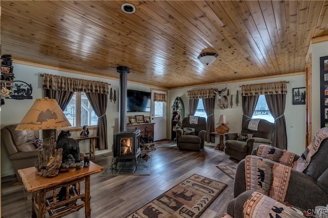 living area featuring wooden ceiling, wood finished floors, ornamental molding, and a wood stove