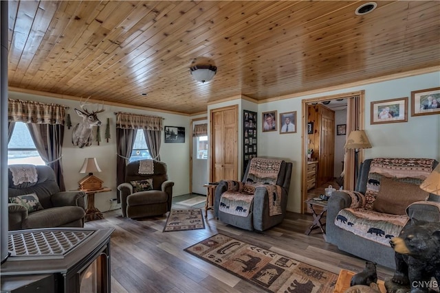 living area with wood finished floors, wood ceiling, and ornamental molding