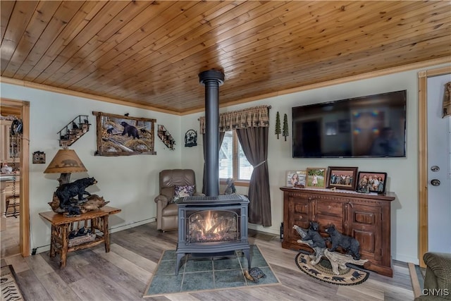 living area featuring wooden ceiling, wood finished floors, ornamental molding, and a wood stove