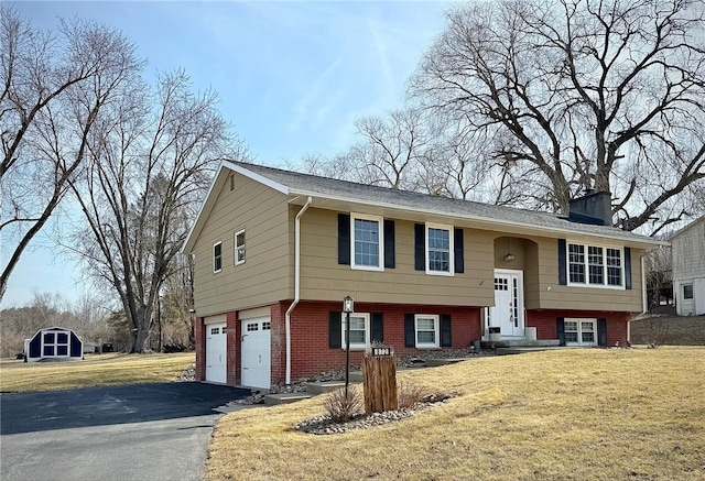 bi-level home with brick siding, aphalt driveway, a front yard, a chimney, and a garage