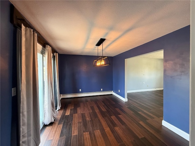 spare room featuring baseboard heating, a textured ceiling, dark wood-type flooring, and baseboards