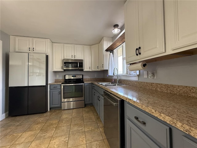 kitchen featuring gray cabinets, a sink, stainless steel appliances, white cabinets, and light tile patterned floors