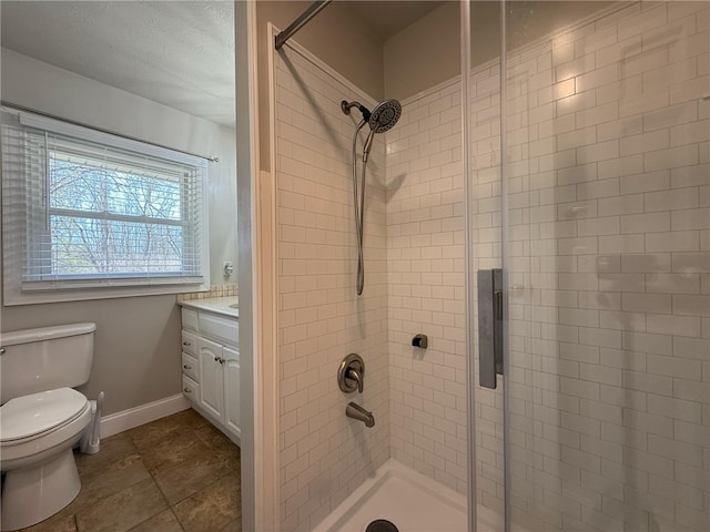 bathroom with vanity, toilet, baseboards, and a stall shower