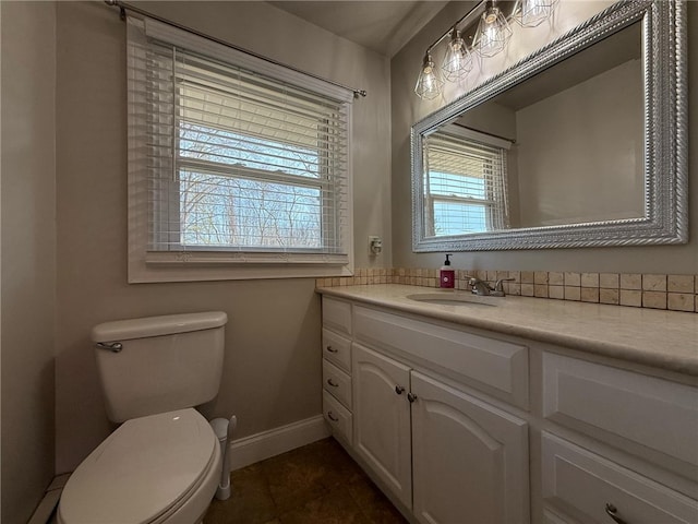 half bath with tile patterned floors, baseboards, toilet, and vanity