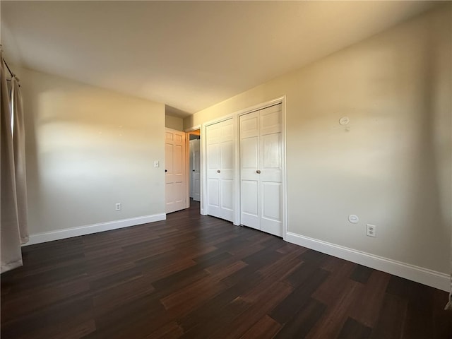 unfurnished bedroom featuring a closet, baseboards, and dark wood finished floors