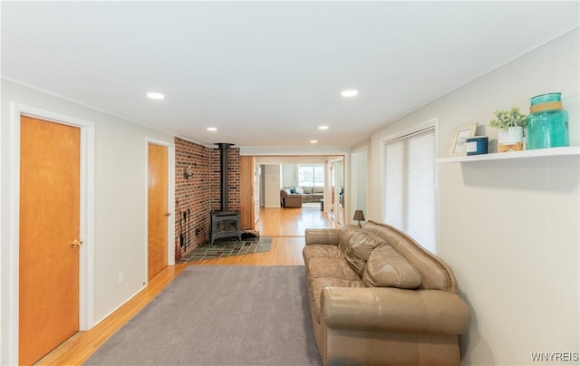 living room with a wood stove, recessed lighting, wood finished floors, and ornamental molding