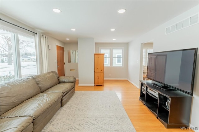 living room featuring baseboards, recessed lighting, visible vents, and light wood-type flooring