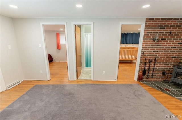 unfurnished living room with visible vents, recessed lighting, a wood stove, and wood finished floors