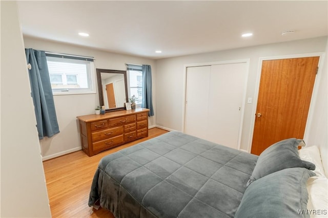 bedroom with a closet, recessed lighting, light wood-type flooring, and baseboards