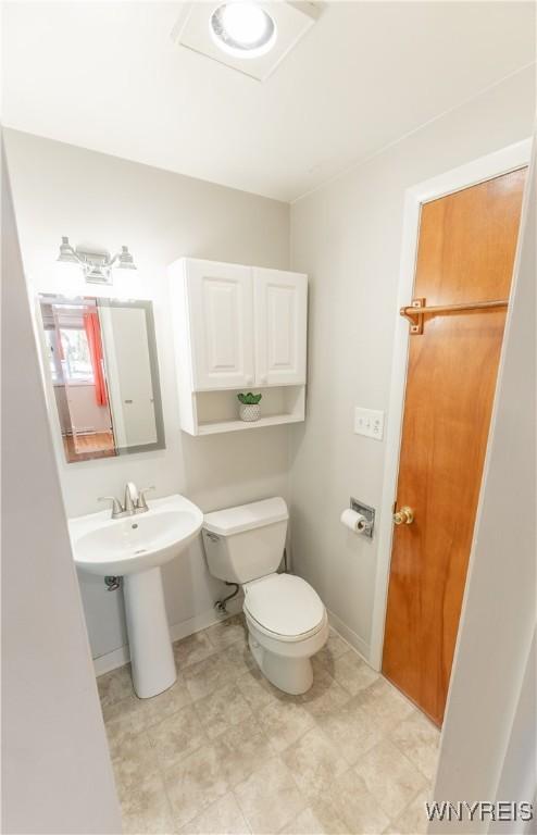 half bathroom with toilet, baseboards, and a sink