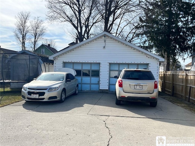 detached garage featuring a trampoline and fence