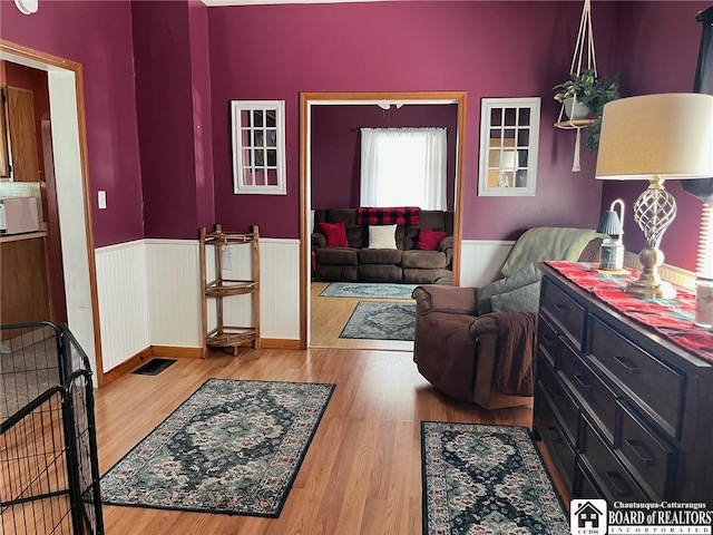 living room with a wainscoted wall and wood finished floors