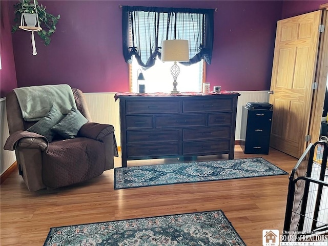 bedroom with wainscoting and wood finished floors