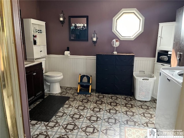 bathroom with wainscoting, washer / clothes dryer, and toilet