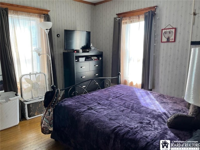 bedroom with wallpapered walls and hardwood / wood-style flooring