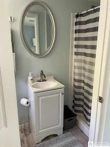 full bathroom featuring a shower with shower curtain, wood finished floors, and vanity