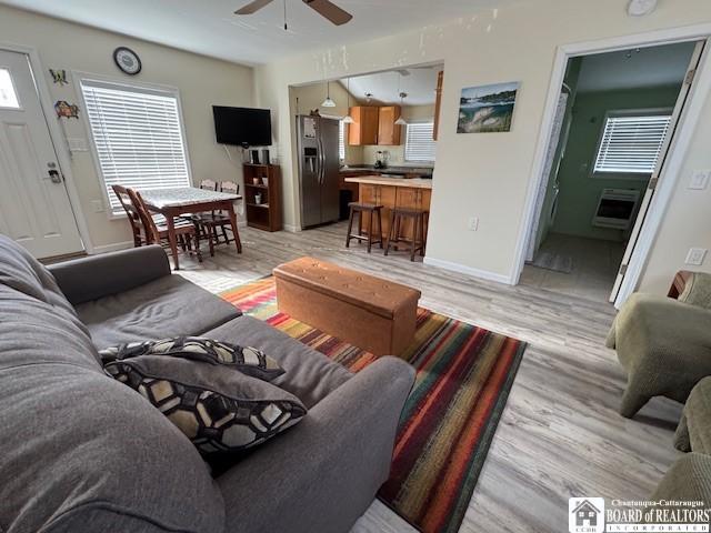 living area featuring a ceiling fan, light wood-style floors, and baseboards