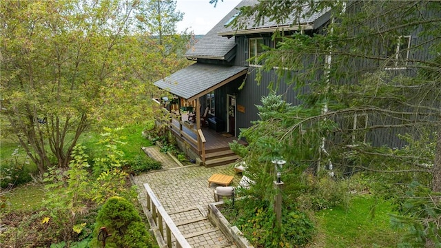 view of property exterior featuring a patio and roof with shingles