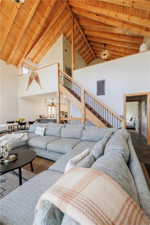 living room with visible vents, beam ceiling, stairway, wood ceiling, and ceiling fan