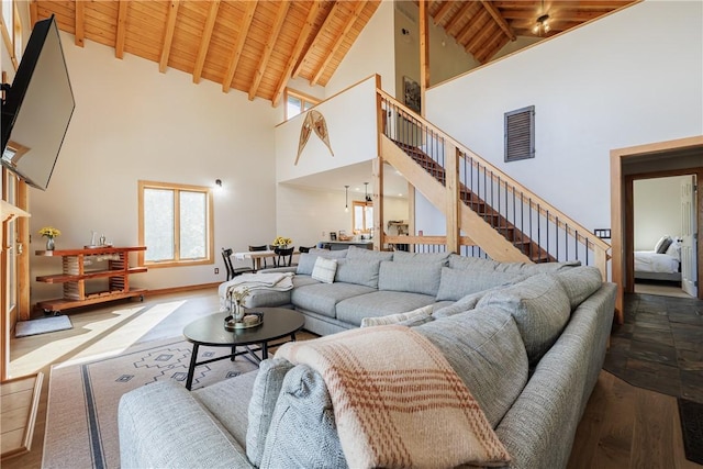 living area featuring vaulted ceiling with beams, baseboards, stairs, wooden ceiling, and wood finished floors