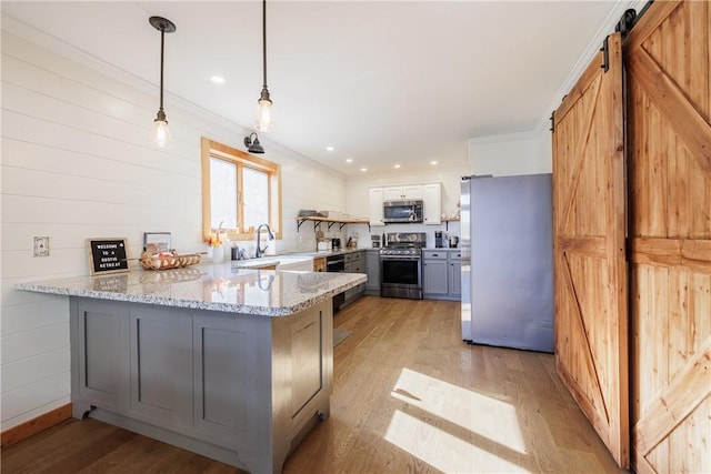 kitchen featuring light stone counters, a peninsula, gray cabinets, light wood-style floors, and appliances with stainless steel finishes