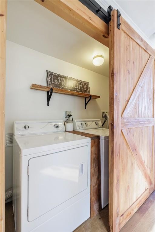 washroom with a barn door, independent washer and dryer, and laundry area