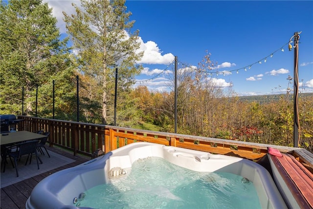 view of pool featuring area for grilling, outdoor dining area, an outdoor hot tub, a deck, and a view of trees