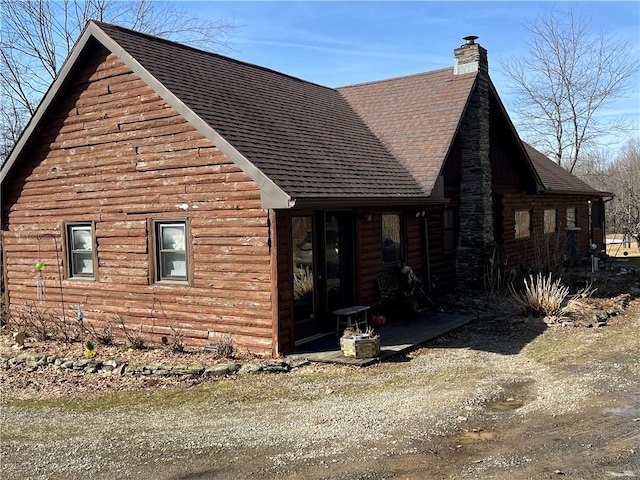 view of side of home with a chimney and roof with shingles