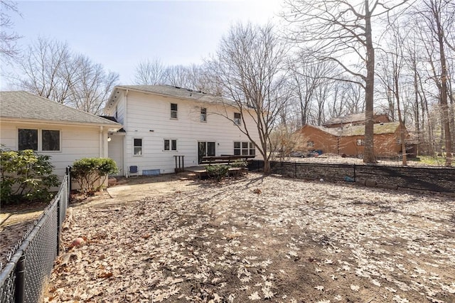 rear view of house featuring fence and roof with shingles