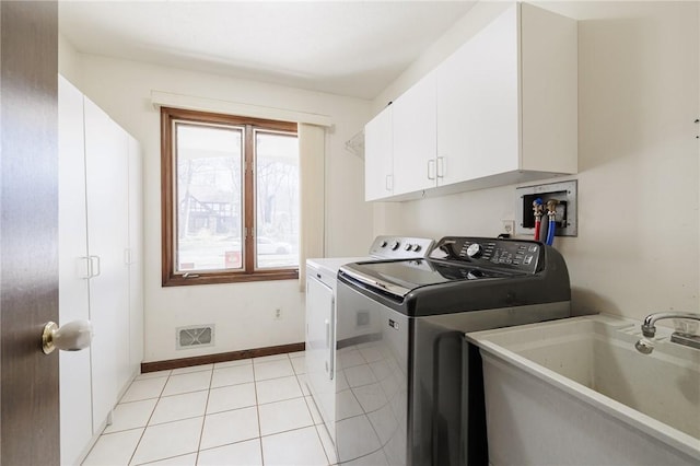 laundry room featuring visible vents, a sink, washing machine and dryer, cabinet space, and light tile patterned flooring