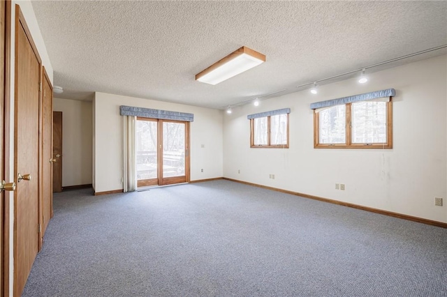 unfurnished room featuring carpet flooring, a textured ceiling, and baseboards