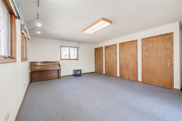 interior space with rail lighting, baseboards, and a textured ceiling