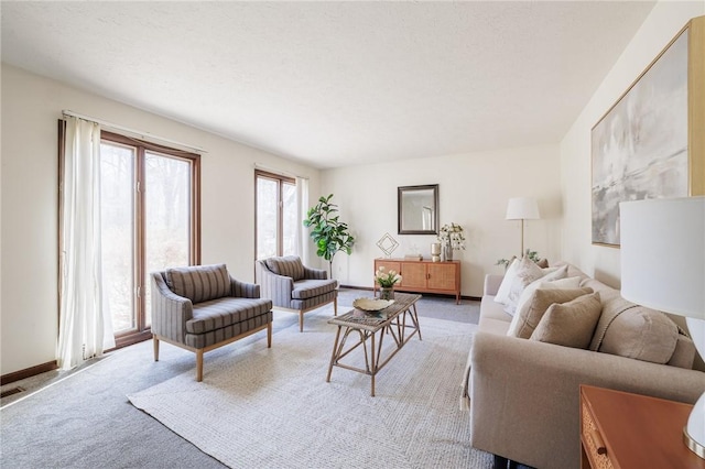 living room featuring light colored carpet, a textured ceiling, and baseboards