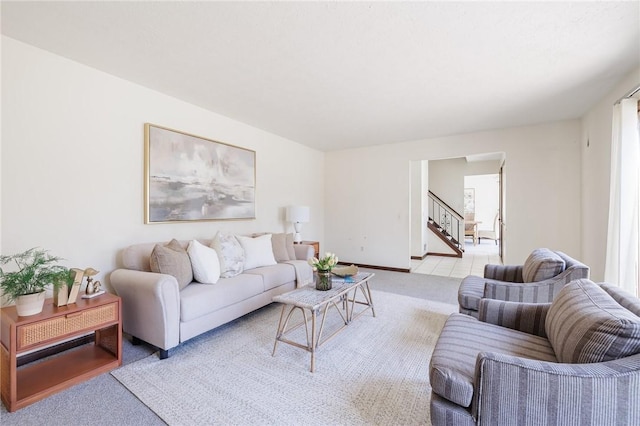 living room featuring stairway, light colored carpet, and baseboards