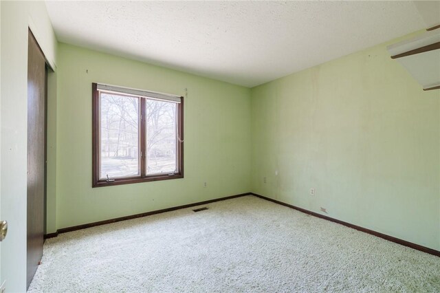 unfurnished room featuring visible vents, baseboards, carpet floors, and a textured ceiling